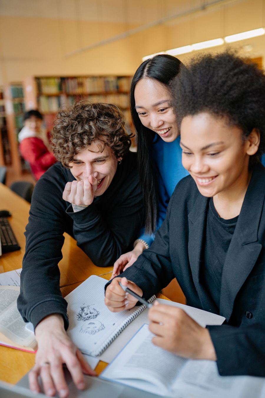 Learners sharing ideas around a laptop in a library